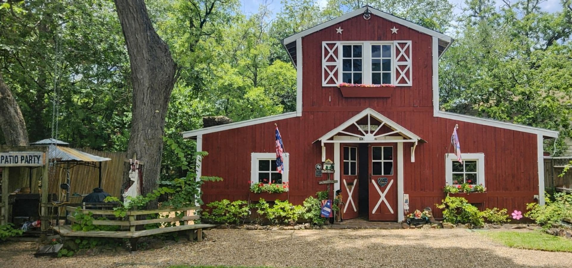 A charming red barn with white accents and flower boxes, surrounded by greenery.