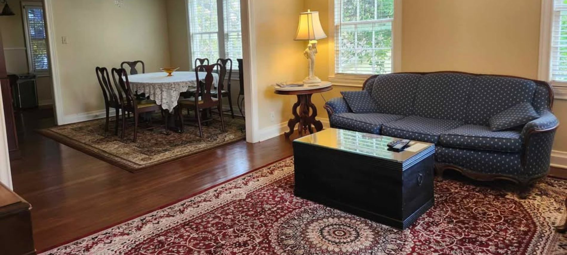 Living room with a black sofa and dining room in background